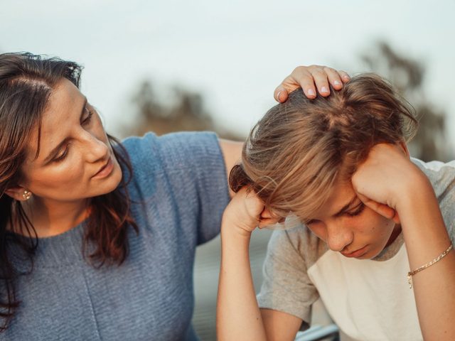 Mutter tröstet ihr nachdenkliches Kind, Hand am Kopf