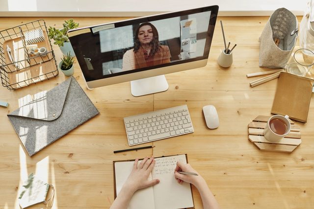 Online-Videoberatung am Bildschirm, dazu Notizen am Schreibtisch