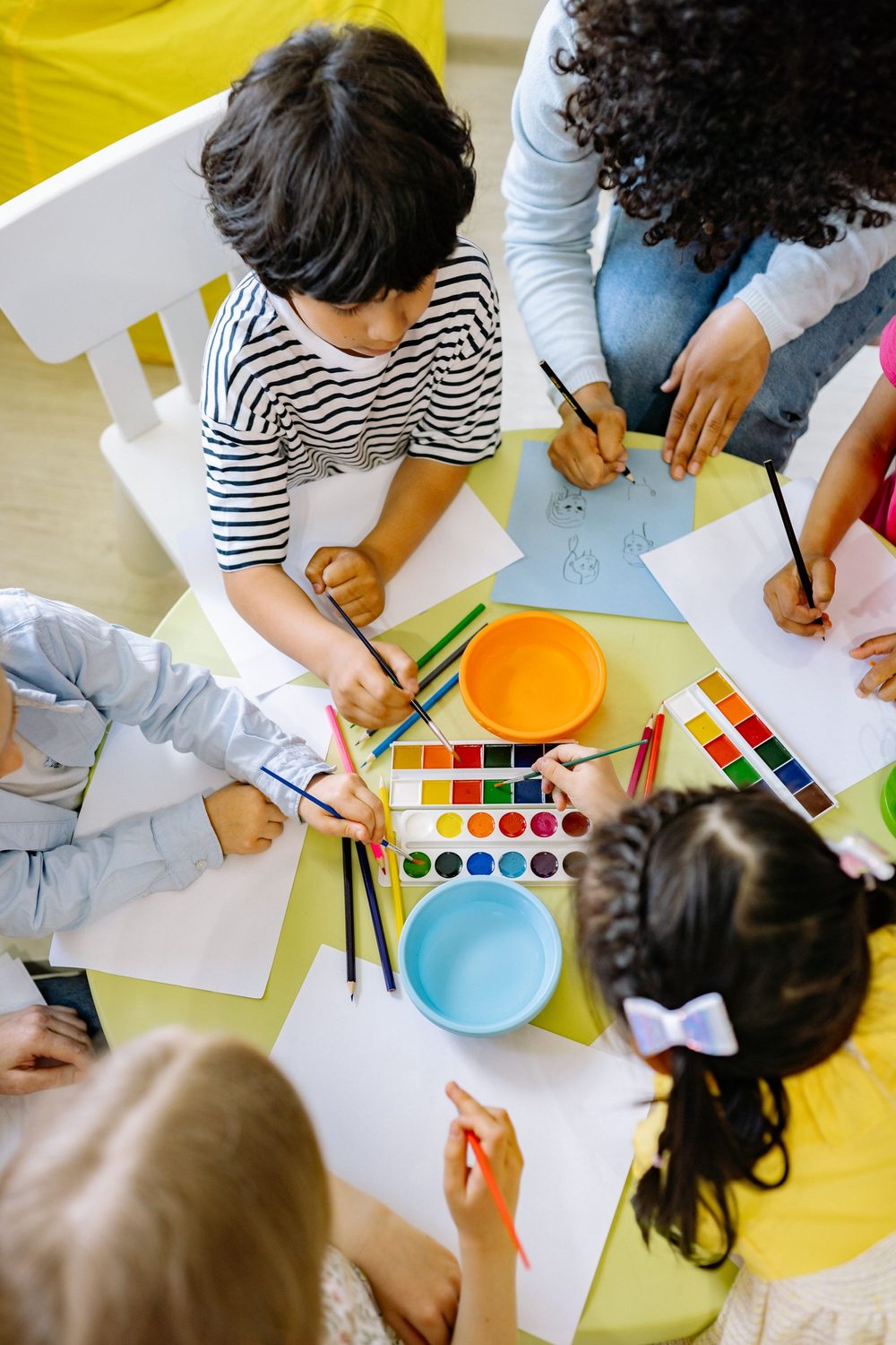 Vorschulkinder malen und üben spielerisch gemeinsam an einem Tisch